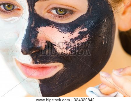 Woman With Clay Carbo Black Mask On One Half Face And White Mud On Second Half. Girl Removing Cosmet