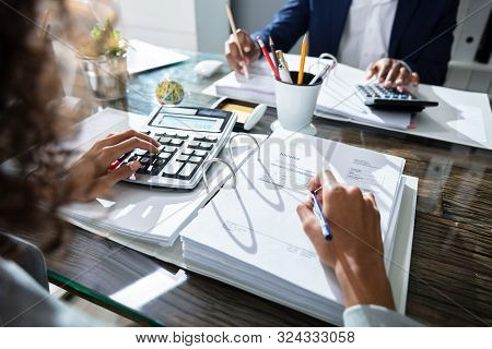 Two Business Colleagues Calculating Tax In Office