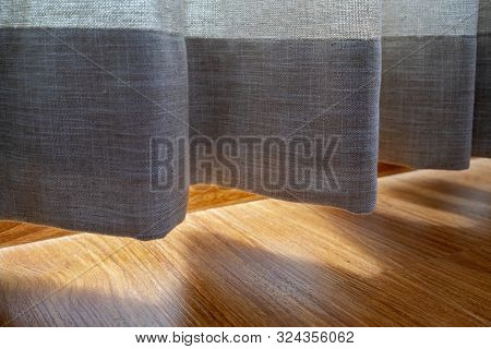 Gray Otton Curtain Near The Wooden Floor On Which The Golden Sunlight Reflection