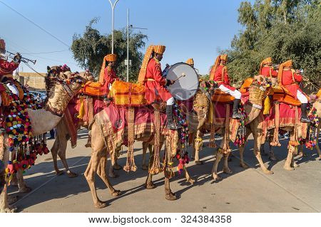 Jaisalmer, India - February 17, 2019: Ceremonial Procession Camels And Riders In Desert Festival In 
