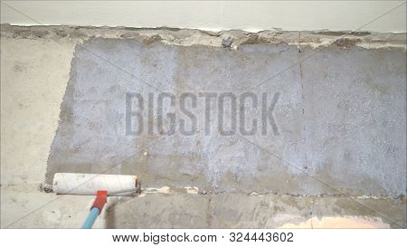 The Process Of Priming A Brick Wall. A Primer Solution Is Applied To A Brick Wall Using A Roller Thu