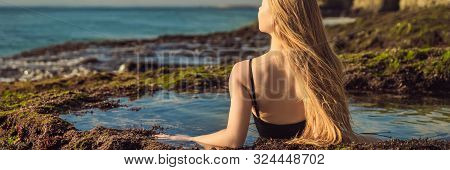 Young Woman Tourist On Pantai Tegal Wangi Beach Sitting In A Bath Of Sea Water, Bali Island, Indones
