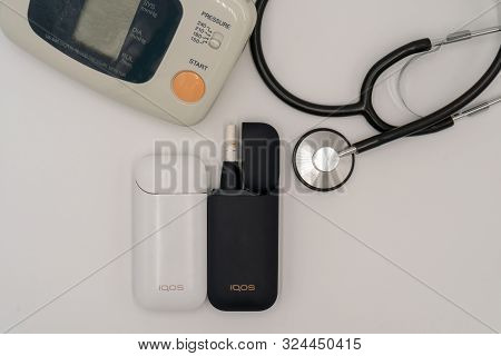 Blood Pressure Tonometer And Iqos On A White Background. The Concept Of Health Damage From Smoking A