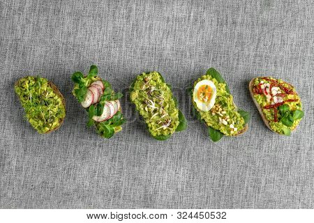 Variety Of Open Bruschetta Sandwiches With Avocado, Soft Boiled Egg, Radish, Spinach, Herbs And Nuts