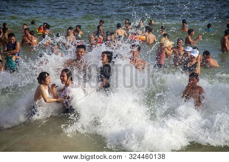 Many Chinese Tourists On The Beach Swim In The Waves