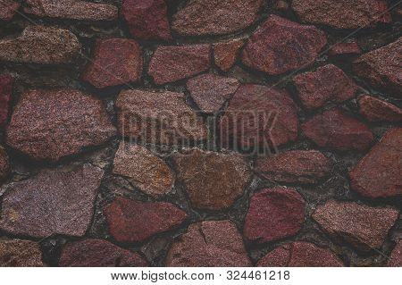 Granite Stone Wall Texture Background. Foggy Faded Dark Red Natural Stones.
