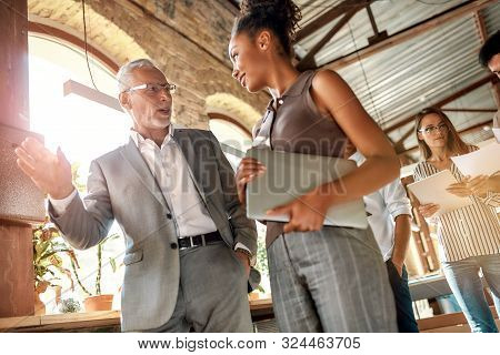 Business Professionals. Two Colleagues Discussing New Project While Walking Standing In The Office C