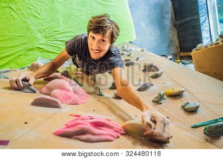 Muscular Man Practicing Rock-climbing On A Rock Wall Indoors