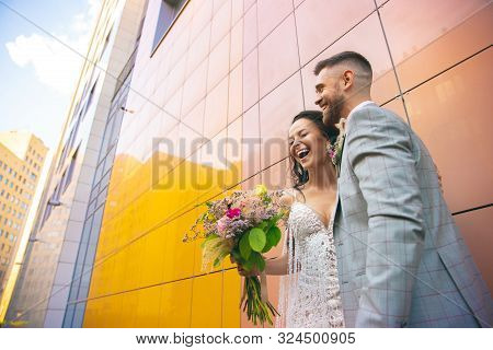 Caucasian Romantic Young Couple Celebrating Marriage In City. Tender Bride And Groom On Modern Citys