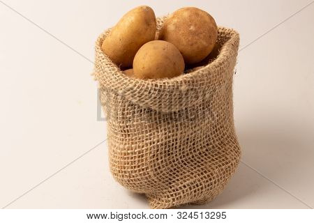 Fresh And Raw Potatoes In A Rustic Sack Isolated On White Backgroud..