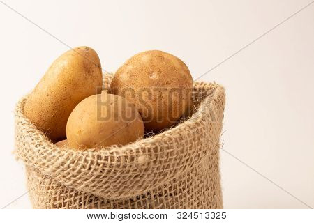 Fresh And Raw Potatoes In A Rustic Sack Isolated On White Backgroud..