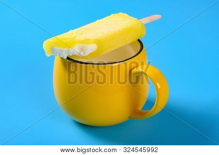 Yellow Popsicle With Couple Of Bites On A Cup On Blue Background