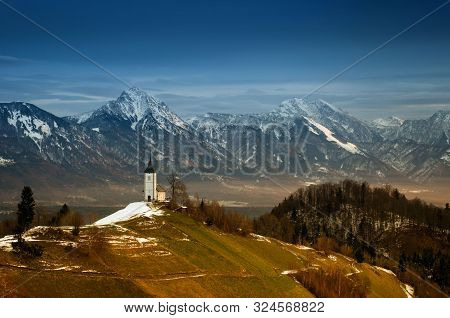 Panoramic View At St. Primus And Felician Church In Jamnik, Julian Alps, Slovenia