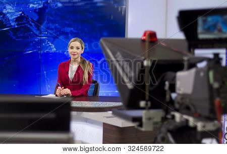 News Anchor In The Tv Studio . Beautiful Girl Reading The News, On A Blue Screen Background