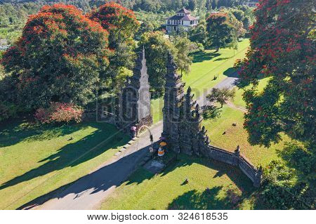 Aerial View Of Bali Handara. The Hindu Temple With Ancient Gate With Pathway In Park Garden At Noon.
