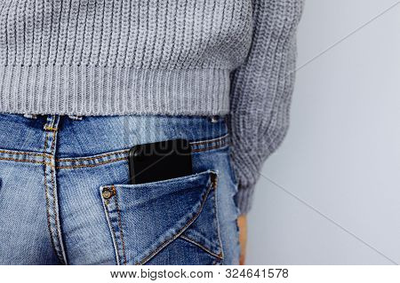 A Mobile Phone In The Back Pocket Of A Jeans On A Girl In Casual Clothes. Mobile Phone In Jeans Pock
