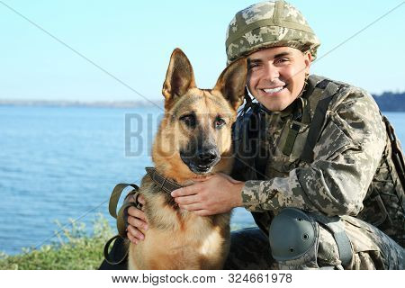Man In Military Uniform With German Shepherd Dog Near River
