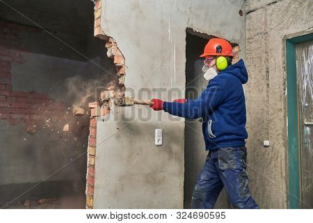 demolition work and rearrangement. worker with sledgehammer destroying wall