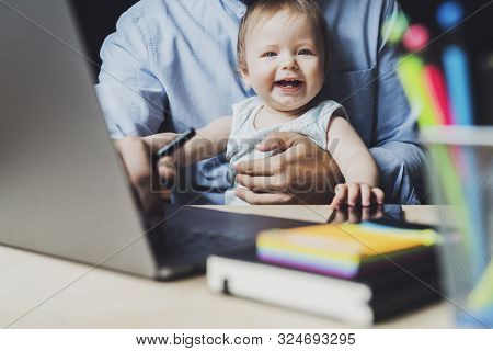 Father Working On Laptop With Baby Sitting On His Knees.smiling Toddler In Front Of Laptop. Workplac