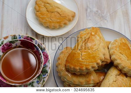 Freshly Baked Sochni On White Plates Served With Tea. White Wooden Background, High Resolution