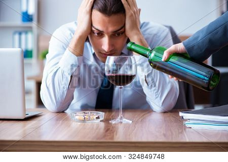 Male employee drinking alcohol and smoking cigarettes at workpla