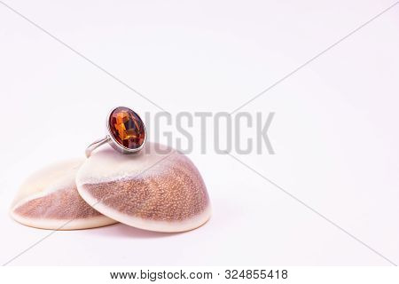 Gemstone Ring Concept. Cinnamon Stone Ring On Seashell With White Background