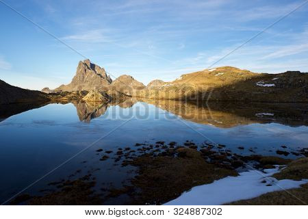 Midi Dossau Peak reflected in a lake. Ossau Valley, Pyrenees National Park, Pyrenees, France.