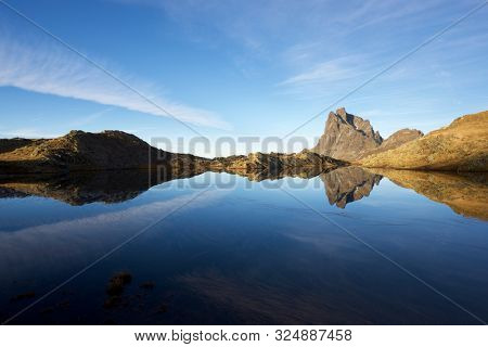 Midi Dossau Peak reflected in a lake. Ossau Valley, Pyrenees National Park, Pyrenees, France.