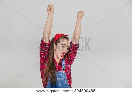 Extremely Happy Stylish Girl In Red Is Raising Her Hands, Bouncing Joyfully, Shouting Hurray.