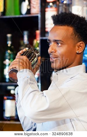 African Bartender Male Holding In Hands A Shaker With A Fresh Delicious Cocktail. Bartender Shaking 