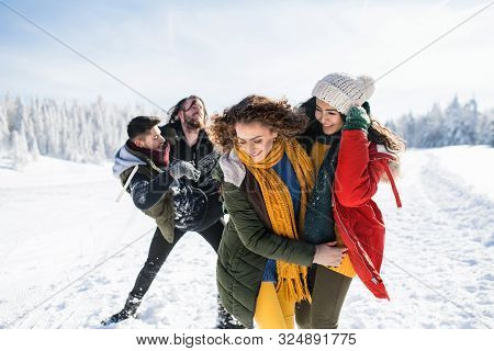 A Group Of Young Friends On A Walk Outdoors In Snow In Winter Forest.