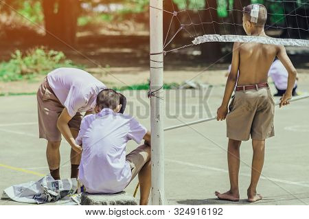 Male Students Use Small Paint Rollers To Paint Yellow Lines On The Cement Floor For Sepak Takraw Tra