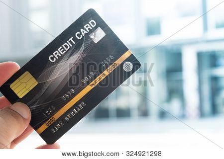 Man Holding Credit Card  With Supermarket Background. Concept Of Shopping
