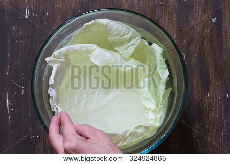 Top View Of Cabbage Leaves In Hot Water Before Stuffing On Brown Background