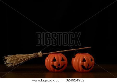 Two Pumpkins And A Witch Broom On Black Background. Happu Halloween