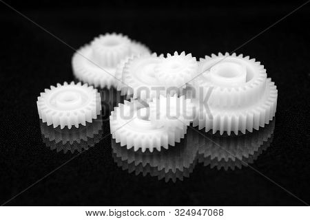 Several White Plastic Gears On A Black Mirror Background. Mechanical Repair. Fix. Reflection. Repair