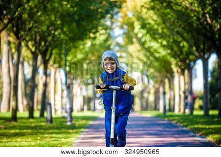 One Handsome Boy Riding A Scooter In An Autumn Park