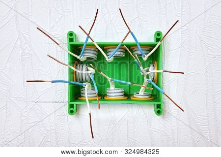 Electrical Work, Installation Of Household Wiring. Many Copper Wires Protrude From The Green Junctio