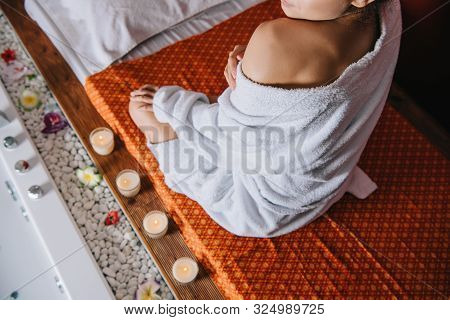 Cropped View Of Woman In Bathrobe Sitting On Massage Mat In Spa Salon