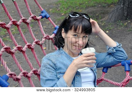 Young Beautiful Woman In Pakra On A Walk, Lies In A Hammock And Drinks Coffee. Summer. Lifestyle