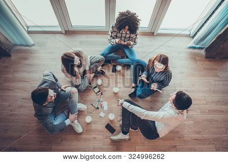 Five Employees Sitting On The Floor With Legs Crossed And Doing Brainstorming. On Foreheads Sticker 
