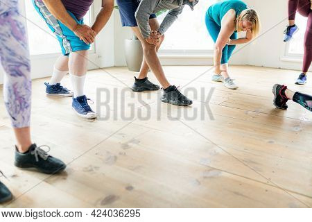 Group of people doing quadriceps stretching in class
