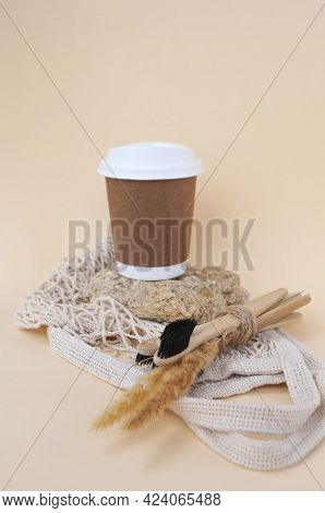 Brown Sustainable Paper Coffee Cup, Reusable Shopping Bag And Wooden Toothbrush On A Natural Stone O