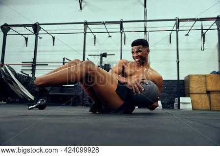 African American Male Doing An Intense Workout In The Gym. Male Athlete Doing Sit-ups With Medicine 
