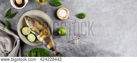 Raw Fish Sea Bass Or Lingcod And Seasonings For Cooking It On A Gray Background Top View, Copy Space