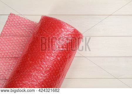 Bubble Wrap Roll On White Wooden Background, Top View. Space For Text