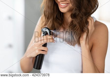 Unrecognizable Woman Styling Hair With Spray Standing In Bathroom Indoor