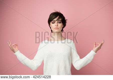 Young pretty woman meditate over pink background. Relaxation, piritual practice and yoga