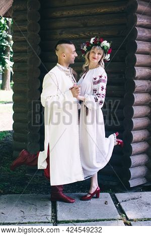 Young People Are Posing In Traditional Folk Costumes. Cossacks Man And Woman In Wreaths And Embroide