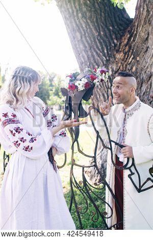 Young People Are Posing In Traditional Folk Costumes. Cossacks Man And Woman In Wreaths And Embroide